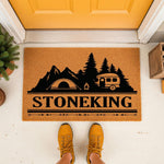 Personalized camping doormat with a mountain, tent, and camper van design on a natural coir fiber welcome mat, perfect for outdoor porch decor and camping enthusiasts looking for a custom last name entrance rug for their home.