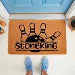Bowling themed doormat featuring a black ball and pins design on natural coir fiber, personalized with a family name for a fun front porch welcome mat that makes a great housewarming gift for any bowling enthusiast or sports fan.