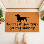 Dachshund doormat with funny Sorry if you trip on my wiener text, featuring a black dog silhouette on a natural coir welcome mat placed at a front door entrance for a humorous home decor look that dog lovers and pet owners will