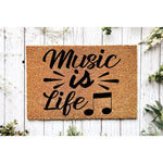 Music is Life coir doormat featuring black script text and musical notes on a natural fiber welcome mat, displayed on a rustic white wood background for a stylish entryway decor look that music lovers will truly enjoy.