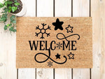 Winter Welcome Doormat with snowflake and star designs on natural coir fiber, featuring a festive holiday entry rug for your front porch decor that adds a cozy seasonal look to your home entrance during the cold winter months.