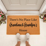 Grandma and Grandpa house doormat featuring a natural coir fiber texture, personalized front porch decor with a welcoming message for grandparents, placed on a white entryway floor with garden gnomes and flowers in the background.