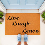 Funny Live Laugh Leave doormat for front porch, featuring a natural coir fiber welcome mat with black script text, placed outside a blue door with a person wearing light blue sneakers standing on the rug for a humorous home entry.