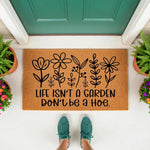 Funny garden doormat with floral line art and the text Life Isn't A Garden Don't Be A Hoe, this natural coir welcome mat is a humorous outdoor rug for your front porch entry, perfect for housewarming gifts or home decor