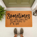 Funny doormat with rude quote about self care on a natural coir fiber welcome mat, placed on a front porch with a green door and fern, perfect for a sarcastic home decor entryway or a blunt housewarming gift for a friend.