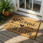 Funny welcome to our shitshow doormat made of natural coir fiber, featuring a bold black script design with an arrow and heart icon for a humorous front porch decor piece that serves as a unique housewarming entry rug for your