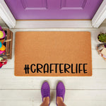 Crafter life doormat with a natural coir fiber texture and black text, featuring a fun hobby theme for a front porch entrance, placed on a white floor in front of a purple door with yarn and craft supplies nearby for a cozy home