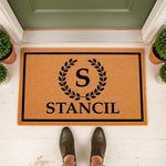 Personalized family name doormat featuring a custom initial inside a black laurel wreath design on a natural coir welcome mat, perfect for a front porch entryway, housewarming decor, or a stylish custom outdoor floor rug for your