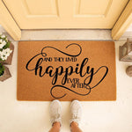 Happily Ever After doormat for a front porch, featuring a natural coir fiber welcome mat with black script text, perfect for a wedding or housewarming entry decor, shown on a doorstep with a person wearing casual sneakers