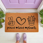 Peace Love Plants doormat featuring a hand-drawn peace sign, heart, and potted succulent design on natural coir fiber, perfect as a funny outdoor welcome mat for plant lovers and gardeners placed at a purple front door entrance.