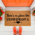 Grandma doormat with There is no place like Grandma's text and a heart arrow design, featuring a natural coir fiber welcome mat on a white porch, perfect for a front door entrance or a housewarming gift for a beloved grandmother.