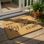 Funny tiny humans escape doormat for front porch, featuring natural coir fiber material with bold black text.