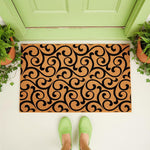 Black and tan swirl pattern coir doormat placed at a front door entrance, featuring a durable natural fiber welcome mat design with a stylish scroll motif that adds a decorative look to any porch or entryway floor decor.