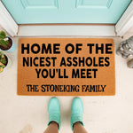 Personalized funny doormat with the text Home of the Nicest Assholes You Will Meet and a custom family name, featuring a natural coir fiber welcome mat design for a front porch entrance that adds humorous decor to any home