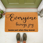 Funny welcome doormat with the text Everyone brings joy some just when they leave, featuring a natural coir fiber texture on a front porch, making this a humorous housewarming gift or outdoor entryway decor for your home entrance.
