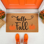Hello Fall pumpkin doormat for autumn porch decor, featuring a natural coir welcome mat with black script text and orange pumpkin graphics placed on a white front porch with orange shoes and potted mums for seasonal home entry.