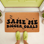 Same Me Bigger Goals doormat featuring bold black retro typography and star accents on a natural coir fiber welcome mat, perfect for a front porch entryway or housewarming decor to inspire daily motivation at your front door.