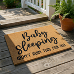 Baby sleeping doormat with funny text, a natural coir fiber welcome mat for new parents that features bold black lettering reading Baby sleeping don't ruin this for us, a humorous front porch decor piece for a nursery or home