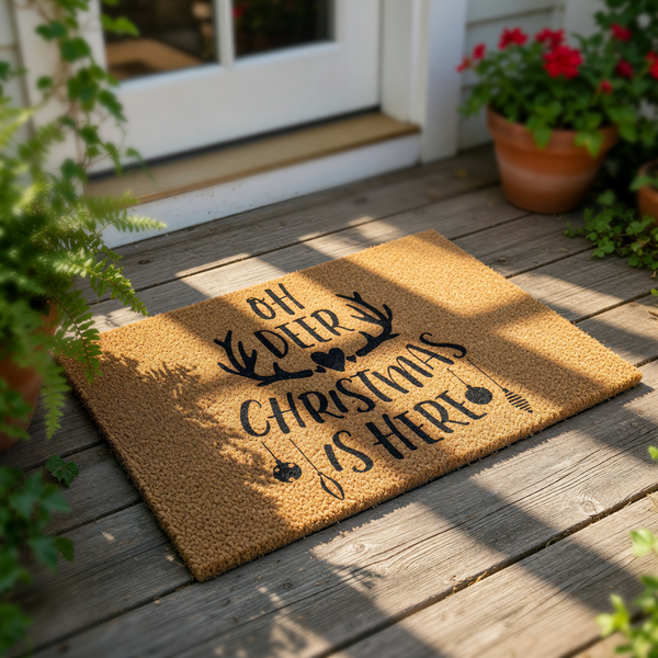 Oh Deer Christmas Is Here doormat with black text and antler design on a natural coir fiber mat, perfect for holiday porch decor, winter entryway rugs, and festive home entrance mats for the Christmas season and winter holidays.