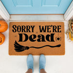 Sorry We're Dead Halloween doormat featuring a spooky broom and spider design on natural coir fiber, perfect for a fall porch welcome mat decor that adds a funny seasonal touch to your front door entrance for the autumn holiday.