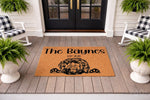 Personalized dog breed doormat featuring a shaggy doodle illustration and custom family name on a natural coir welcome mat, displayed on a front porch with rocking chairs and potted ferns for a stylish home entryway decor look.