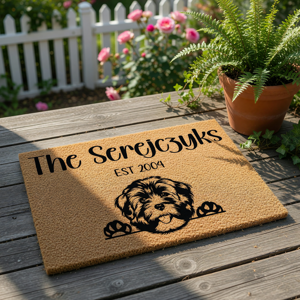 Personalized family name doormat featuring a cute dog illustration on natural coir fiber, this custom welcome mat makes a charming porch decor piece for pet lovers, displayed on a rustic wood deck with a potted fern and garden