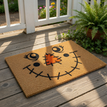 Scarecrow face doormat for fall porch decor, featuring a natural coir welcome mat with a stitched orange nose and smiling mouth design, perfect for autumn home entryways and seasonal outdoor floor mats on a wood deck.