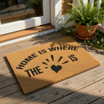 Home is where the heart is coir doormat with black text and a heart icon, featuring a natural fiber welcome mat design for front porch decor, housewarming entry rug, and rustic farmhouse style floor mat for your home entrance.