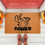 Oh My Gourd I Love Fall doormat featuring a pumpkin design on natural coir fiber, perfect for autumn porch decor, seasonal entryway mats, and funny fall home welcome mats placed on a white wood porch with pumpkins and red door.