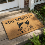 Personalized cat welcome doormat featuring a cute kitten illustration and paw prints on natural coir fiber, this custom family name outdoor rug is a durable entrance mat for cat lovers and pet owners placed on a porch.