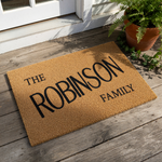 Personalized family name doormat featuring custom text on natural coir fiber, this durable outdoor welcome mat is a stylish housewarming gift for a front porch entrance, adding a rustic touch to your home decor and entryway floor.