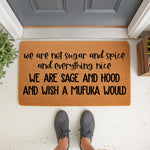 Funny doormat with bold black text reading we are not sugar and spice and everything nice we are sage and hood and wish a mufuka would, displayed as a natural fiber welcome mat on a porch floor for a sassy home decor entryway
