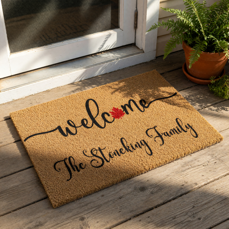Personalized family name doormat featuring a natural coir texture, black cursive welcome text, and a red maple leaf icon, making a stylish custom outdoor welcome mat for your front porch entrance or home entryway decor.