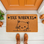 Personalized cat doormat with a cute kitten illustration and custom family name text on a natural coir welcome mat, perfect for a front porch entryway, featuring paw prints and a friendly waving cat design for pet lovers.