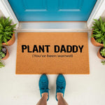 Plant Daddy coir doormat for houseplant lovers, featuring funny text on a natural fiber welcome mat placed at a front door entrance with potted plants, perfect for a gardener or indoor plant enthusiast home decor entryway.