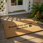 Proud plant parents live here doormat featuring a natural coir fiber texture and black text with a monstera leaf icon, making this funny housewarming welcome mat a great outdoor floor rug for any indoor plant lover home entrance.