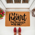 My heart belongs to me doormat featuring bold black text on a natural coir fiber welcome mat, placed on a white porch floor with red shoes visible, creating a funny and stylish front door entrance rug for home decor enthusiasts.