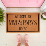 Mimi and Papa house doormat featuring natural coir fiber with black text, this personalized welcome mat for grandparents sits on a porch in front of a pink door, making a stylish entryway rug for a family home or front door decor.