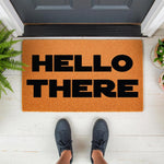 Hello There doormat featuring bold black text on a natural coir fiber mat, perfect as a front porch welcome mat or outdoor entryway rug for a modern home entrance, shown on a white porch floor with a person standing in dark