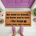 Personalized dog doormat with the funny quote No need to knock we know you are here from the dogs, featuring a natural coir fiber welcome mat design for pet lovers placed on a front porch with a purple door and cute dog-themed