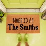 Personalized Married AF doormat for couples, a funny coir welcome mat featuring custom family name text for a housewarming or wedding entry decor, placed on a bright porch with a person wearing lime green sneakers standing on it.