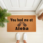 Tropical pineapple welcome doormat featuring the phrase You had me at Aloha in black text on a natural coir fiber mat, placed on a front porch entryway to create a stylish and inviting home decor look for your front door entrance.