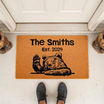 Personalized bear welcome doormat featuring a waving black bear illustration and custom family name text, this durable coir fiber outdoor floor mat adds a rustic cabin look to your front porch entryway decor for new homeowners.