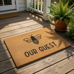 Bee Our Guest doormat made of natural coir fiber, featuring a black insect graphic and bold text for a front porch welcome mat, perfect for a farmhouse entryway, housewarming decor, or a stylish outdoor entrance floor rug.