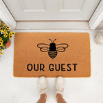 Bee Our Guest doormat featuring a cute bumblebee design on natural coir fiber, this funny welcome mat for front porch entryways adds a stylish touch to your home decor and makes a charming housewarming gift for any bee lover.