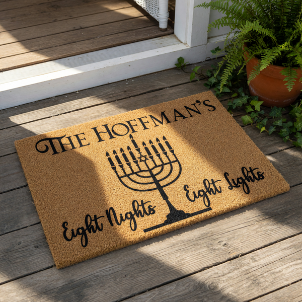 Personalized Hanukkah doormat featuring a black menorah design on natural coir fiber, with the text Eight Nights Eight Lights and space for a family name, making a festive holiday welcome mat for your front porch or entryway