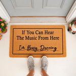 Funny music lover doormat with the text If You Can Hear The Music From Here I am Busy Dancing, featuring a natural coir fiber welcome mat design placed on a front porch for a stylish home entrance decor look for dancers and music