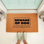 Funny Beware of Dog doormat with a cat warning, featuring a natural fiber welcome mat on a porch with a person standing on it, perfect for pet owners who want a humorous front door rug or a sarcastic housewarming entrance decor