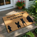 Funny dog doormat with a natural coir texture featuring black silhouettes of a fire hydrant, two dogs, and a bush, with the text There is Some Dogs in This House printed on this durable outdoor welcome mat for pet lovers and home