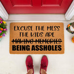 Funny doormat with text Excuse the mess the kids are being assholes, a natural coir fiber welcome mat for front porch decor that makes a humorous housewarming gift for parents who love sarcastic home entry rugs and funny floor